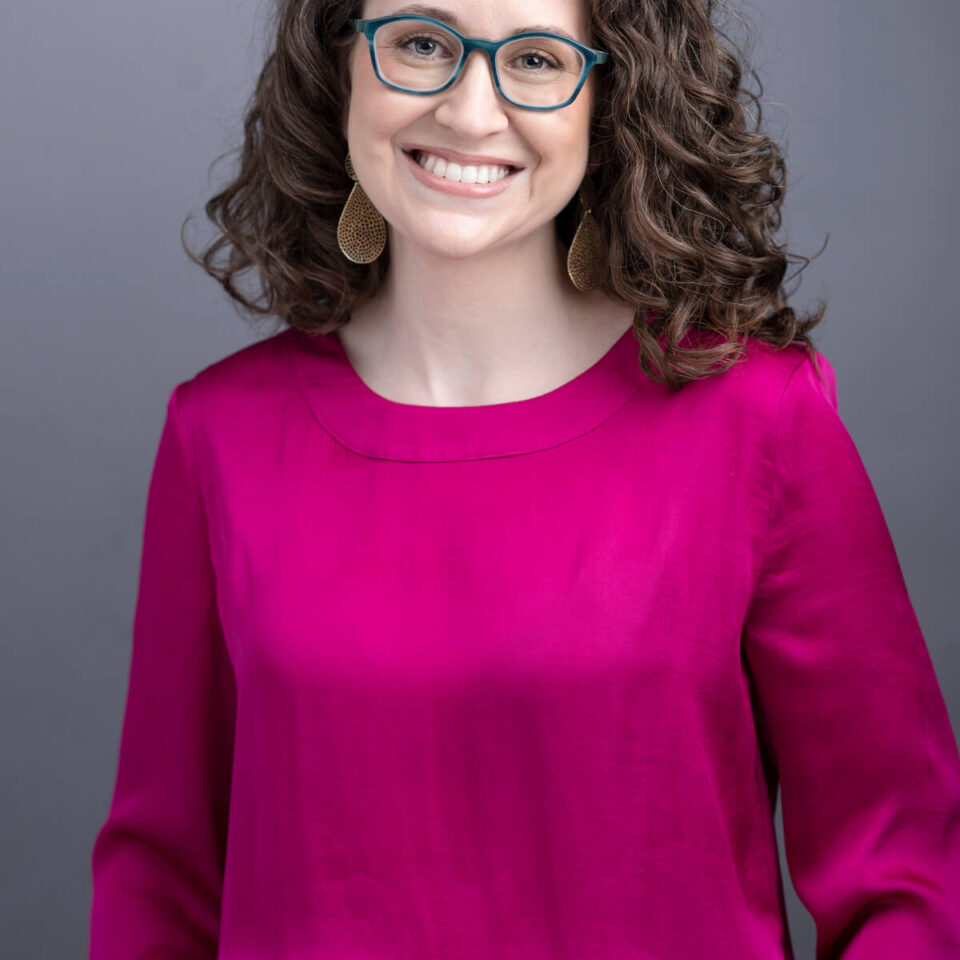 Business Headshot of Women in Pink Top with Brown Hair and Glasses